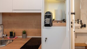 Een functionele keuken met een spoelbak, kookplaat en een klein aanrecht.