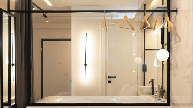 Een moderne hotelkamer met een groot bed, een houten dienblad met ontbijtartikelen en een grote spiegel die de kamer weerspiegelt.