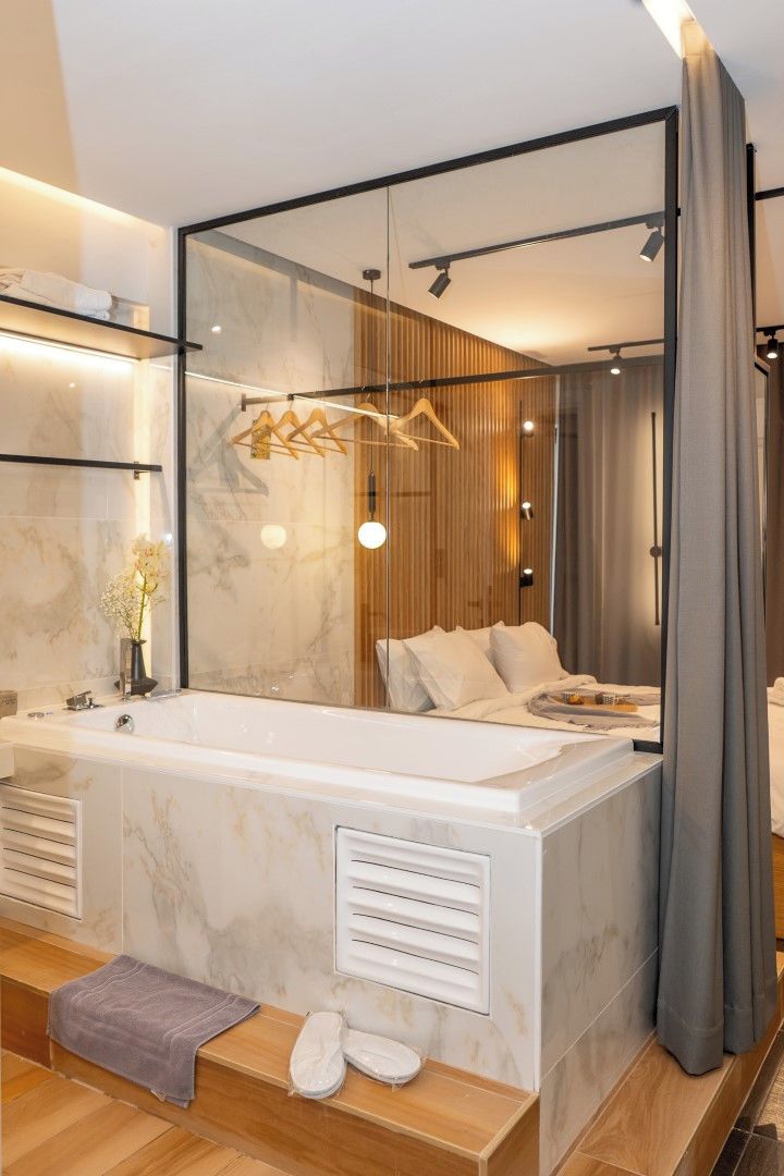 A modern bathroom with a large bathtub, a mirror, and a wooden panel wall.