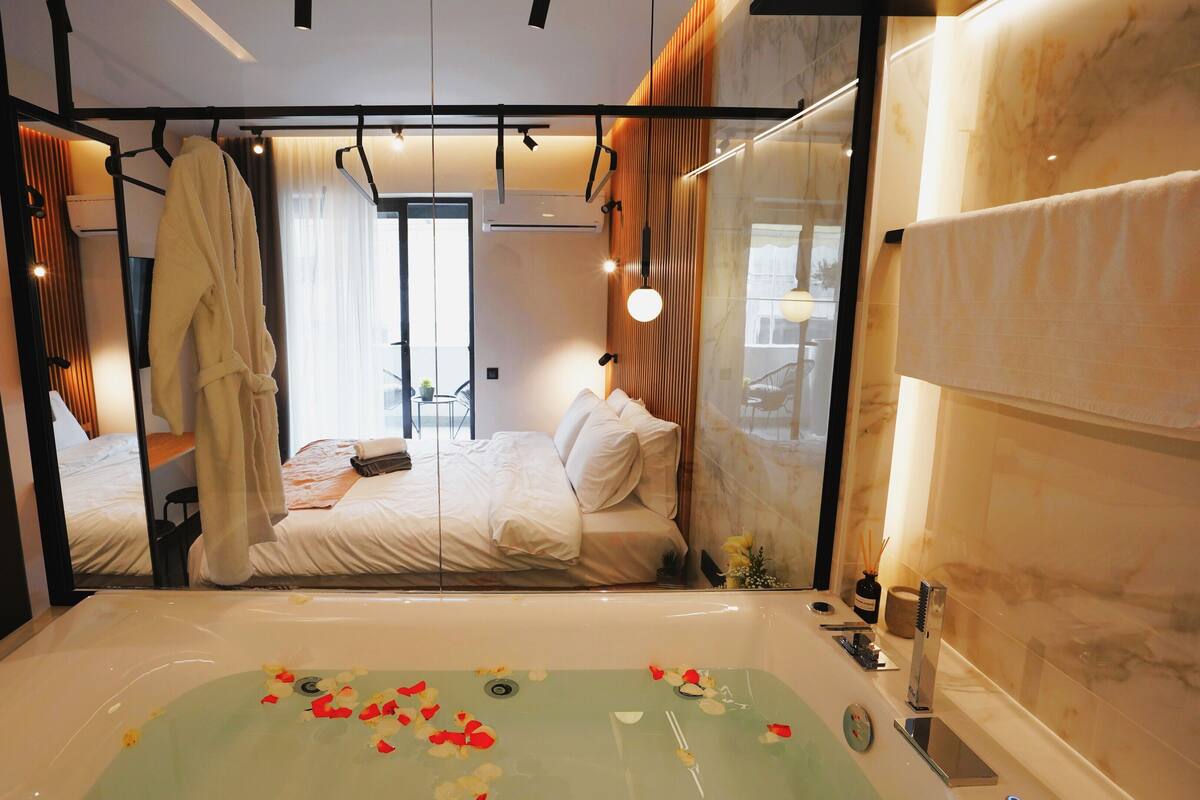 Een moderne hotelkamer met een ruim bad, een bed met witte lakens en een balkon met uitzicht.