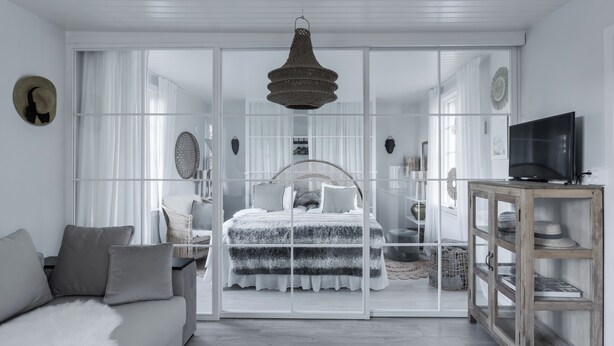 A modern bedroom with a large bed, a television, and a wardrobe. - Pensionat Enehall (Bastad)