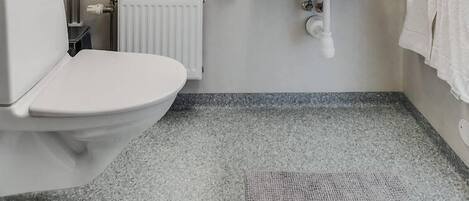 A bathroom with a toilet, sink, mirror, and radiator.