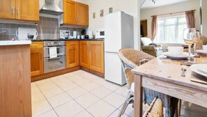 A compact kitchen with wooden cabinets, a stove, and a refrigerator.