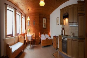 A cozy room with a wooden ceiling, a bed, a small table with chairs, and a kitchenette with wooden cabinets. - Farmhouse in Afritz near Gerlitzen Ski Center (Afritz-Verditz)