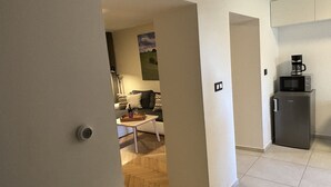 A compact living space with a kitchenette, a dining area, and a seating area with a couch and a coffee machine.