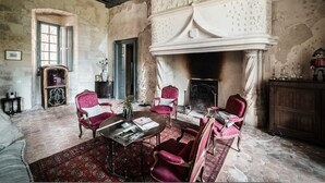 A room with a fireplace, antique furniture, and a stone floor.
