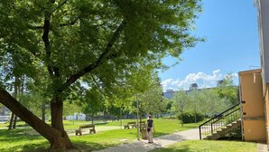 Un parque con un sendero adoquinado, bancos y un árbol grande.