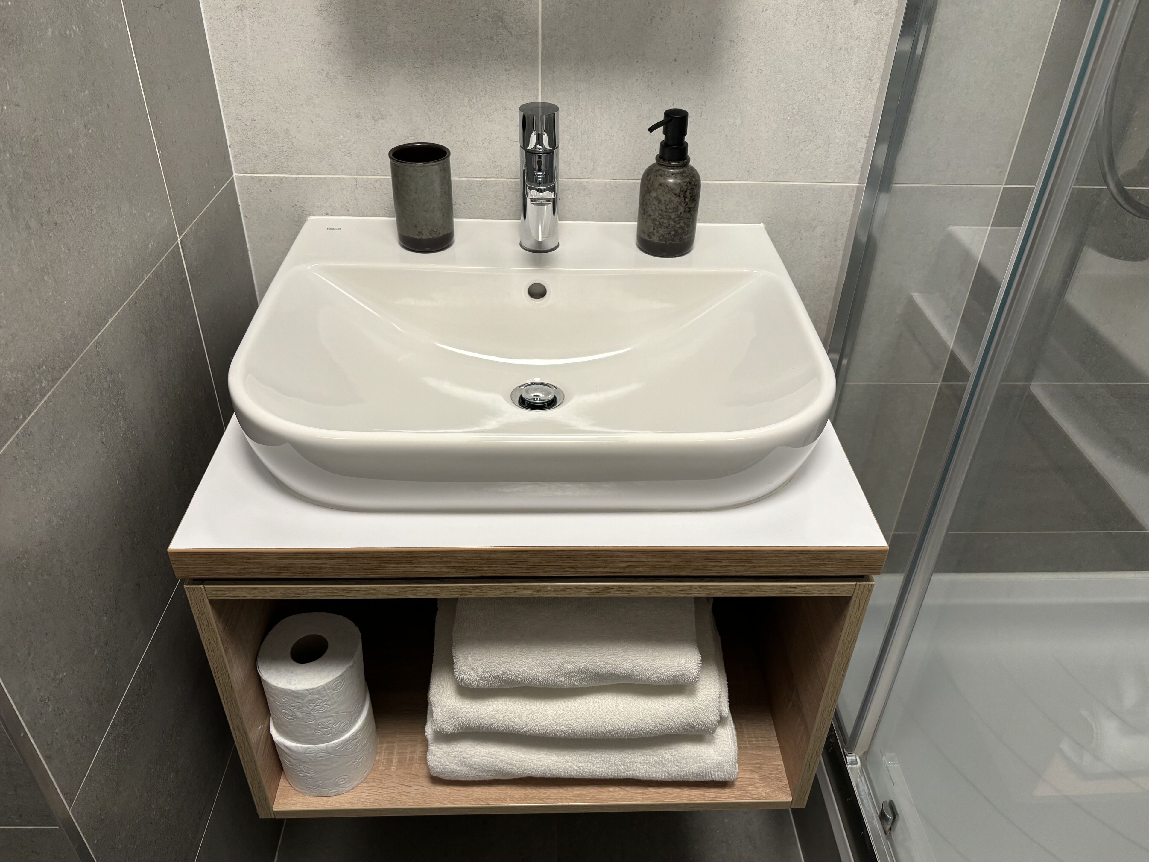 A bathroom with a white sink, a soap dispenser, and a towel holder.