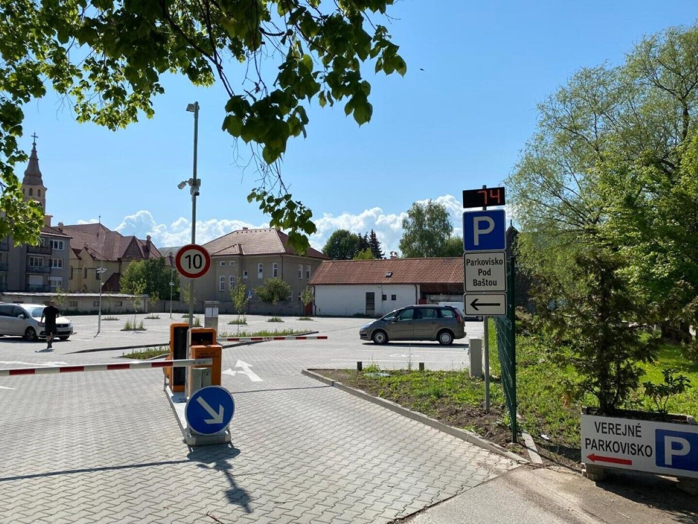Een parkeersbord met een digitaal scherm dat '74' aangeeft, een bord met een snelheidslimiet van '10' en richting pijlen voor parkeren.