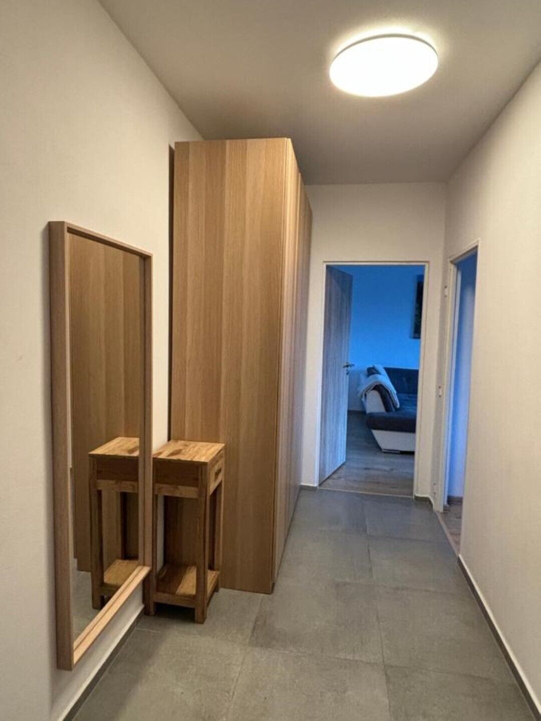 Un couloir avec des armoires en bois et une petite table.