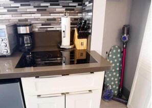 Efficient kitchen with stovetop, coffee maker, and knife block.
