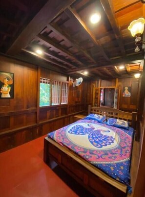 A traditional wooden room with a bed, a fan, and a ceiling fan.