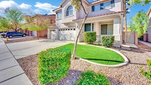 A two-story house with a garage, a well-maintained lawn, and a driveway. - Seven Palms Stylish Home with Pool, Hot Tub,& Movie Room (Henderson)