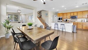 A spacious kitchen with wooden cabinets, a central island, and a dining area with a large wooden table and chairs. - Seven Palms Stylish Home with Pool, Hot Tub,& Movie Room (Henderson)