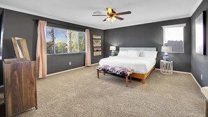A bedroom with a large bed, a ceiling fan, and a view of the outdoors. - Seven Palms Stylish Home with Pool, Hot Tub,& Movie Room (Henderson)