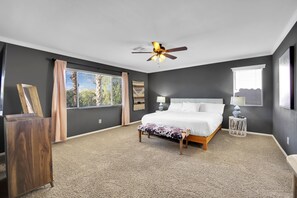 A bedroom with a large bed, a ceiling fan, and a view of the outdoors. - Seven Palms Stylish Home with Pool, Hot Tub,& Movie Room (Henderson)