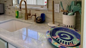 A kitchen with a large window, a sink, and a decorative plate on the counter.