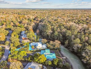 An aerial view of a residential area with houses, a river, and dense forest. - Manatee Cove Main House Star5vacations (Spring Hill)