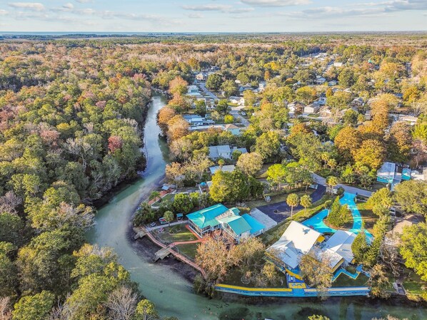Vista aérea de una zona residencial con casas, un río y un complejo de piscinas.