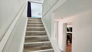 A staircase with wooden steps and white railings, leading to a room with a fireplace. - Manatee Cove Compound Retreat Star5vaca (Spring Hill)