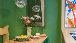 Een eetgedeelte met een houten tafel, een vaas met bloemen en een groene wand.