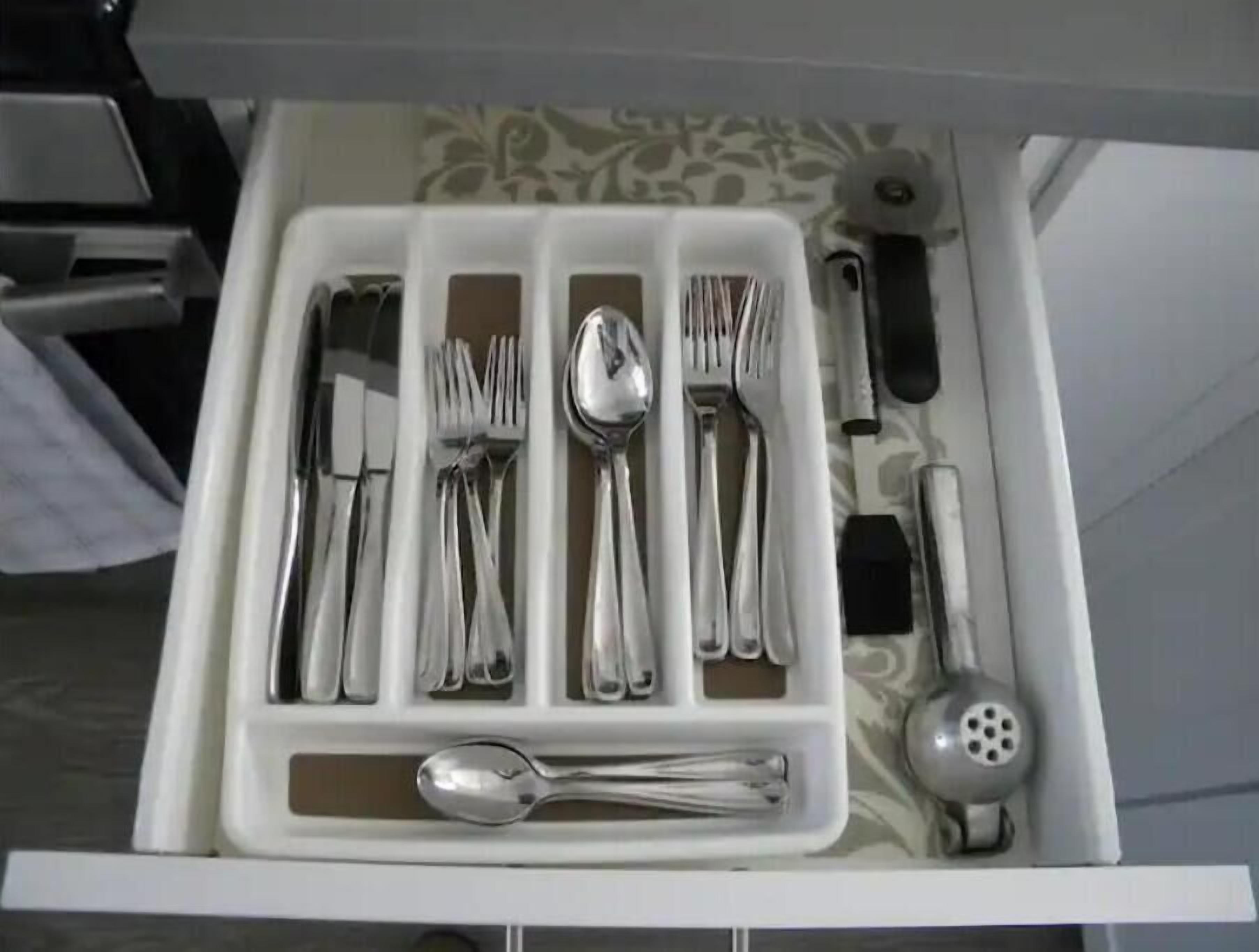 A drawer containing various silverware including forks, spoons, and a knife.