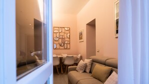 A compact living space with a sofa, dining table, chairs, and a decorative wall piece. - La Casupola - Gemelli Garden

 (Roma)