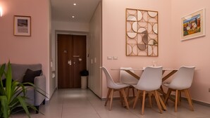 A modern living room with a sofa, a dining table with chairs, a decorative wall piece, and a door leading to another room. - La Casupola - Gemelli Garden

 (Roma)