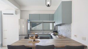 Una cocina moderna con una mesa de comedor de madera, armarios grises y un refrigerador de acero inoxidable.