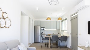 Una cocina moderna con comedor, un sofá y un televisor montado en la pared.