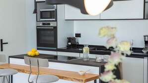 Una cucina moderna con isola centrale, una zona pranzo con tavolo in legno e due sedie, e una macchina da caffè.