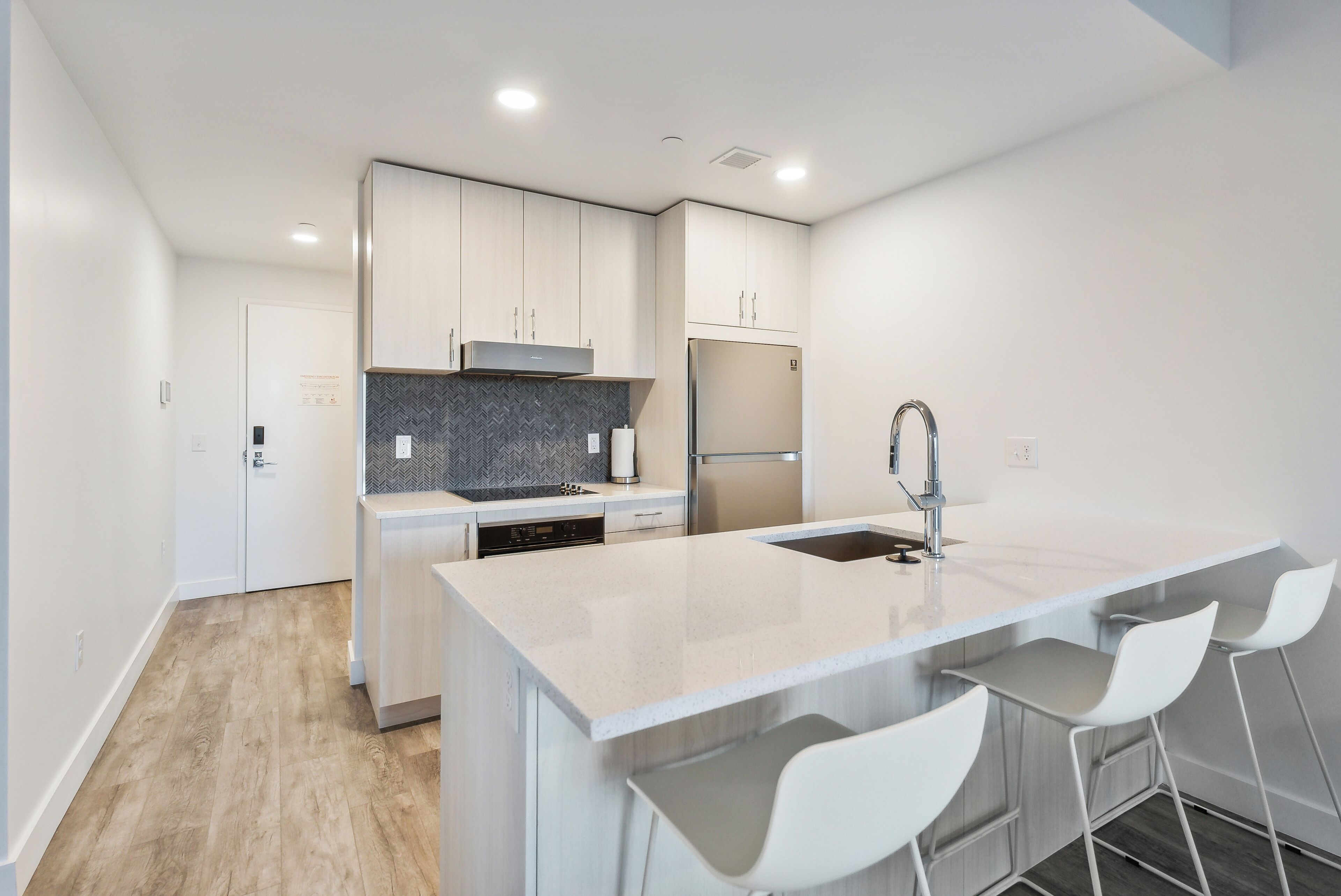 Una cocina moderna con armarios blancos, un refrigerador de acero inoxidable y una encimera de mármol.
