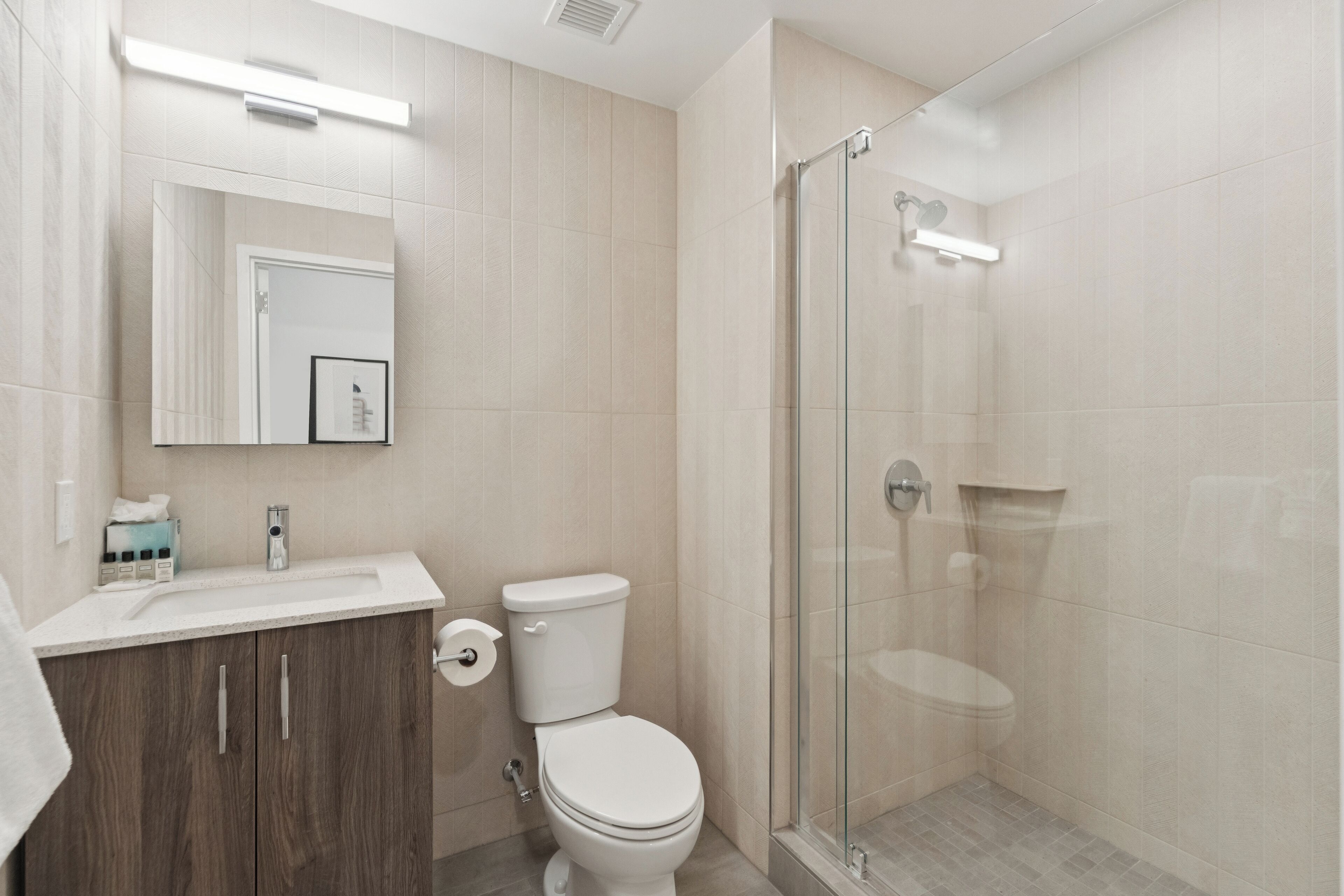 A modern bathroom with a toilet, sink, and glass shower enclosure.