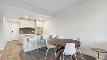Una cocina moderna con armarios blancos, una isla central y un comedor con una mesa redonda y sillas.