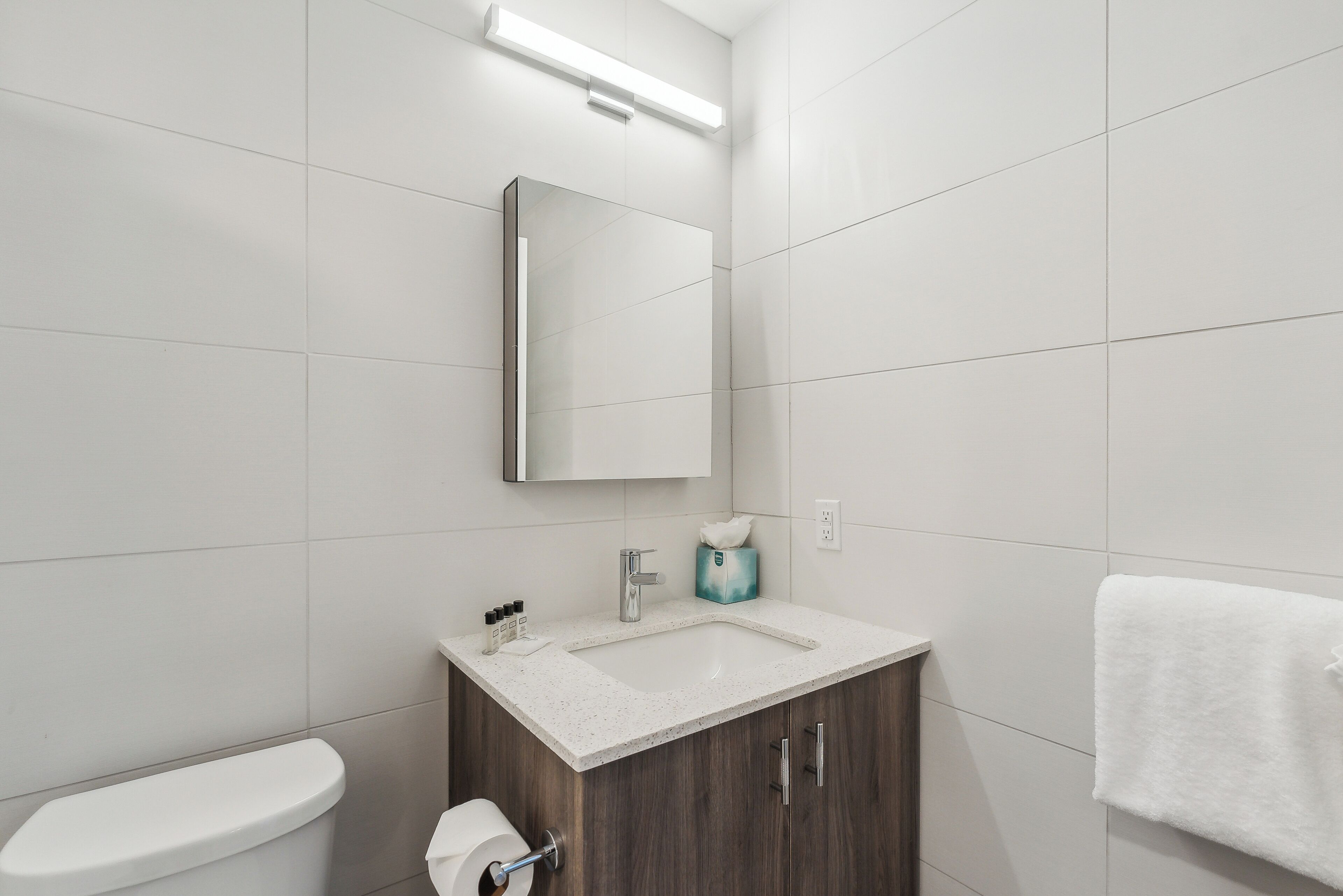 Ein modernes Badezimmer mit Toilette, Waschbecken mit Spiegel und einem Handtuch an der Wand.