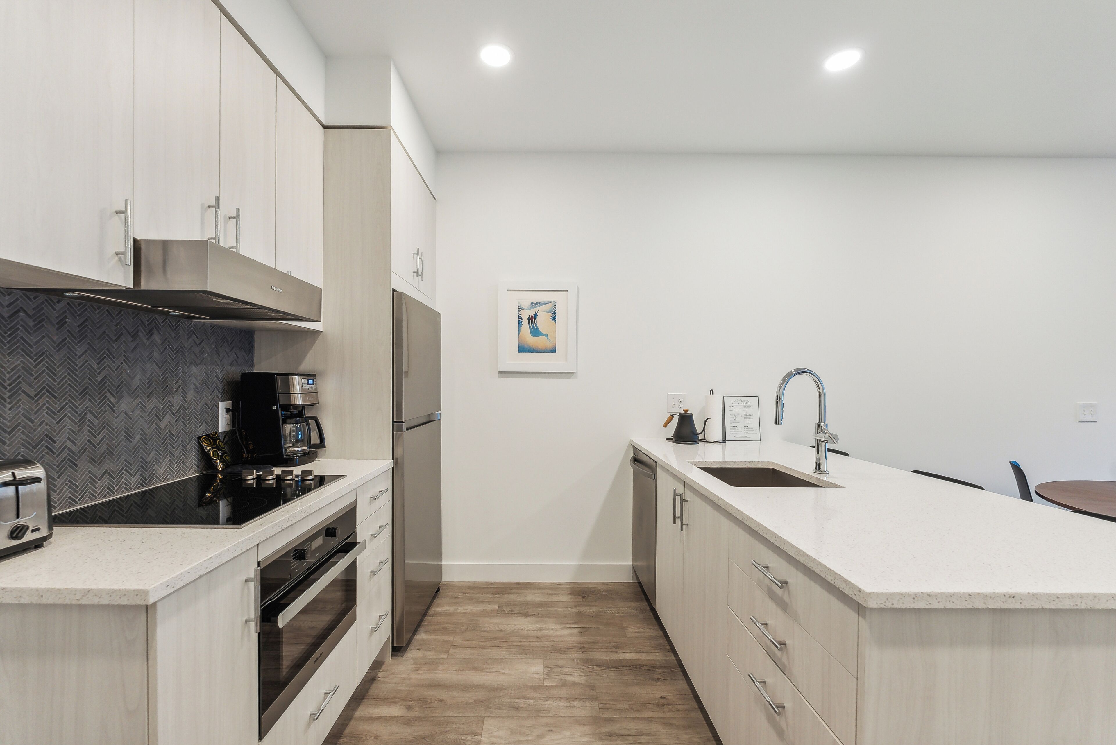 A modern kitchen with stainless steel appliances, a herringbone-patterned backsplash, and a minimalist design.