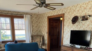 A living room with a blue sofa, a wooden coffee table, and a television on a wooden cabinet. - Sunny, vintage farmhouse in the center of quintessential New England farm town. (Granby)