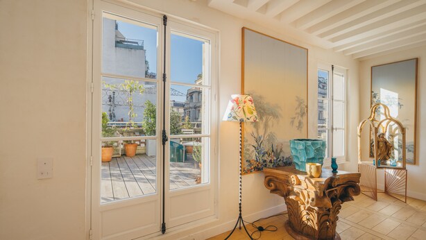 A room with a large window, a standing lamp, and a wooden table with a vase. - 2 storey luxury penthouse with large terrace but no elevator (Paris)