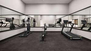A modern gym with cardio machines, weight stations, and a mirrored wall.