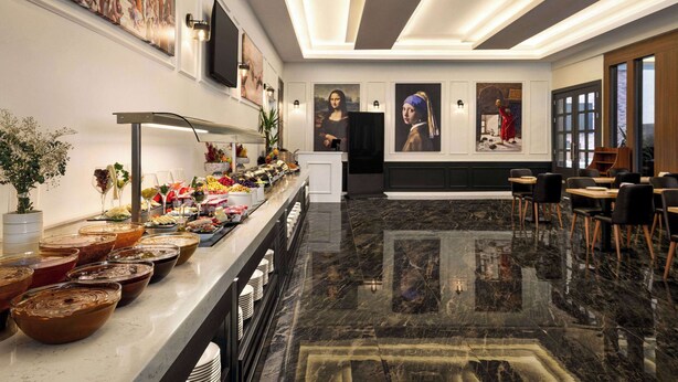 A spacious lobby with a marble floor, a buffet with various food items, and artwork on the walls.