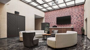 A lobby with a reception desk, seating area, and a large door.