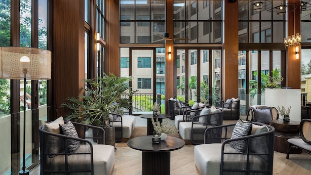 A spacious indoor area with large windows, wicker furniture, and a central coffee table. - The Proud Karon Beach Phuket Trademark Collection By Wyndham (Karon)