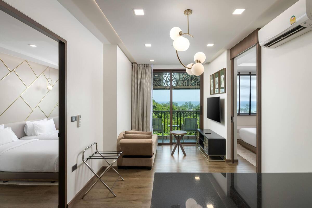 Une chambre d’hôtel moderne équipée d’un lit, d’un canapé, d’un balcon, d’une télévision et d’un coin repas.