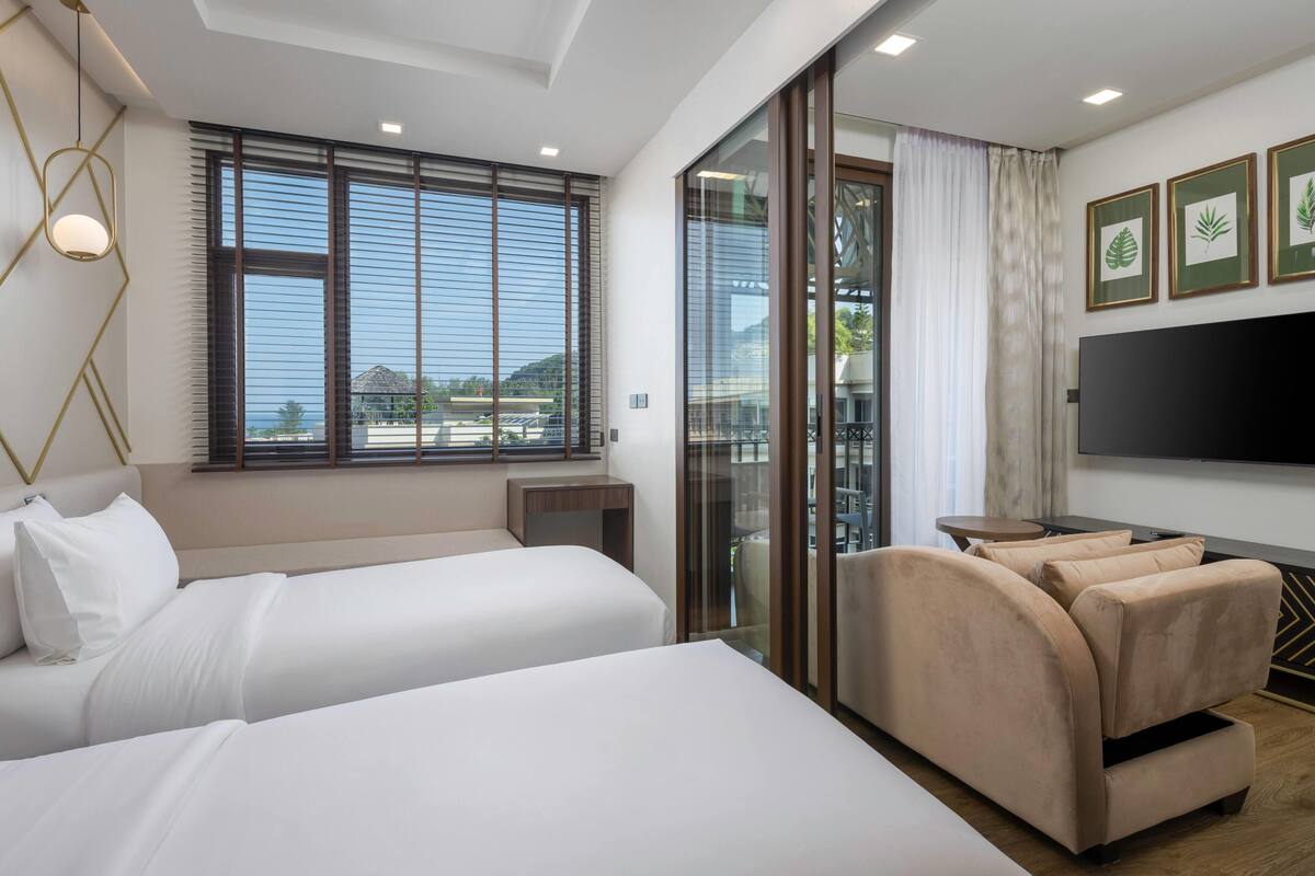 Une chambre d’hôtel avec deux lits, un canapé, une télévision et un balcon avec vue.