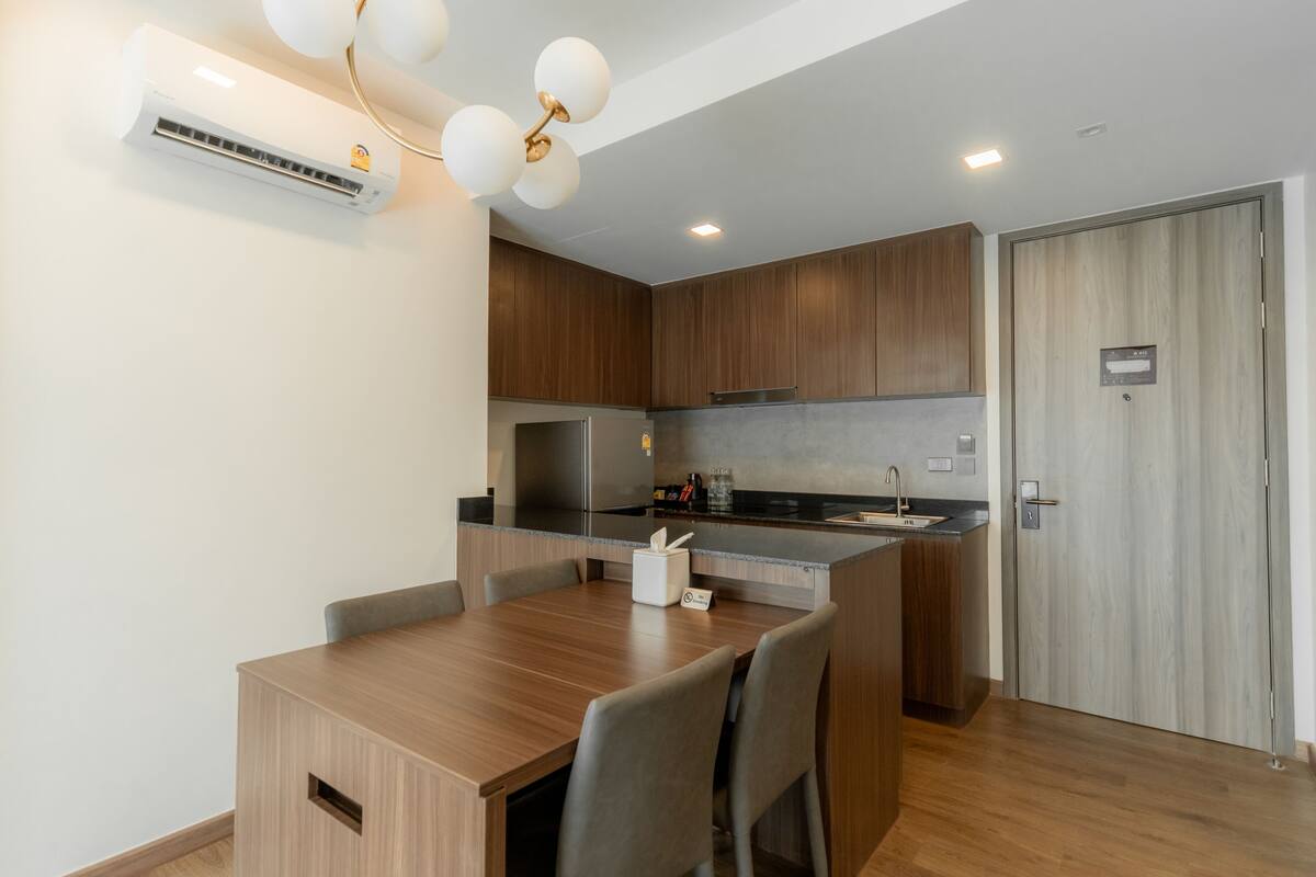 Une cuisine moderne avec des meubles en bois, un réfrigérateur en acier inoxydable et un four encastré.