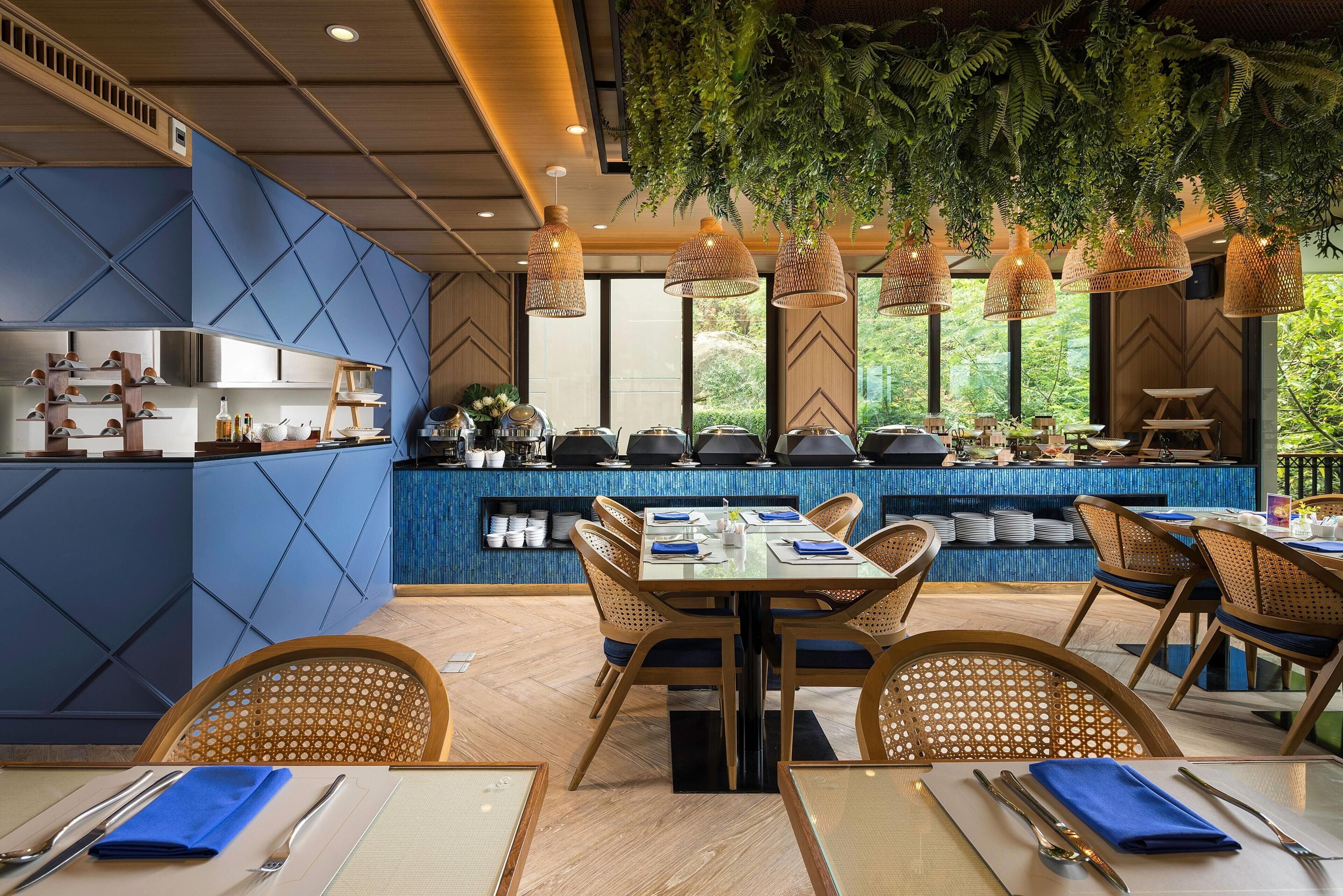 Un restaurant avec un mur bleu, des meubles en bois et des plantes suspendues.