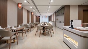 A modern dining area with multiple tables and chairs, a reception desk, and a coffee machine.