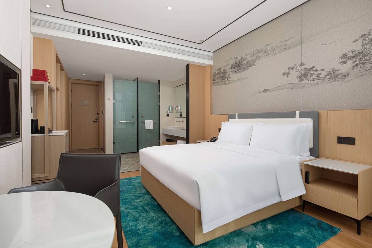 Une chambre d’hôtel moderne avec un grand lit, des tables de chevet, un bureau et une chaise.