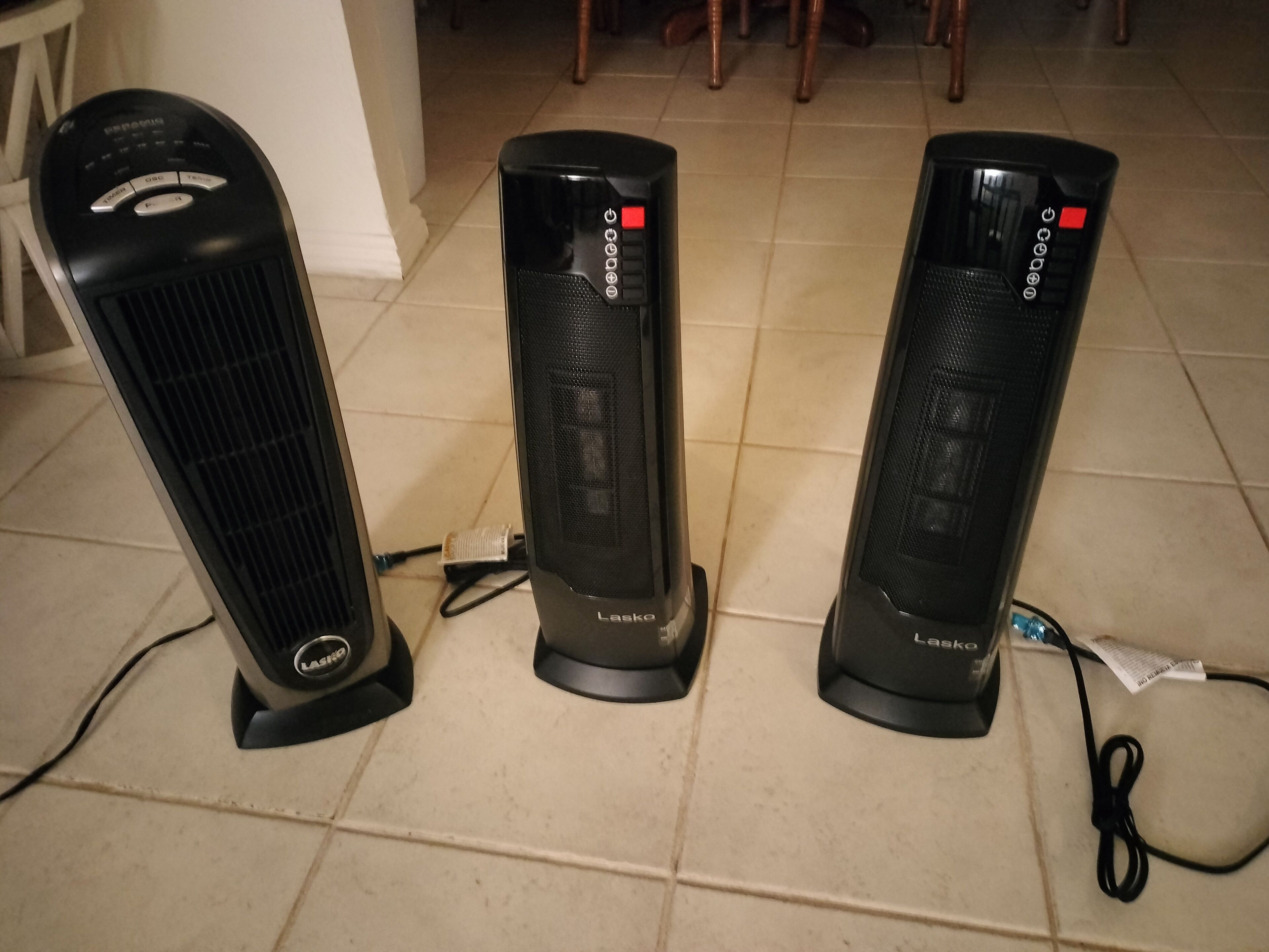 Three standing fans on a tiled floor.