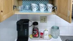 Une cuisine avec des meubles de rangement en bois, une machine à café et divers ustensiles de cuisine sur le plan de travail.